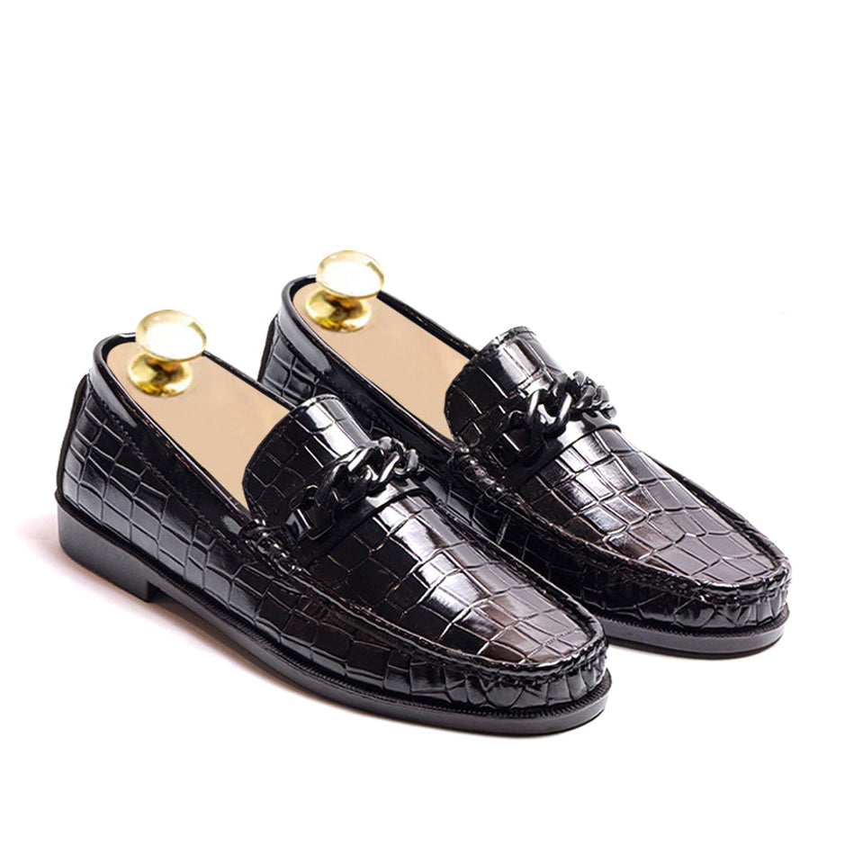Black crocodile-patterned loafers on a white background