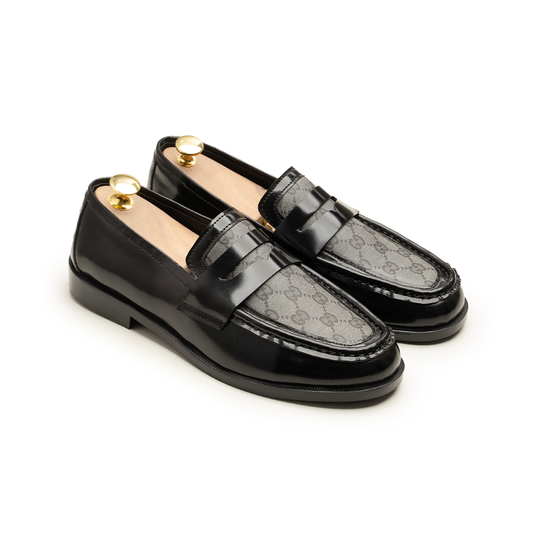 Pair of black loafers with gold accents on a white background